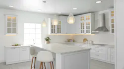 A fully white kitchen with an island in the center.