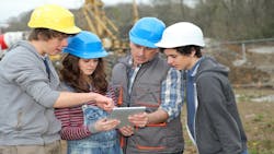 Students in hard hats learn on a construction jobsite Students in hard hats learn on a construction jobsite