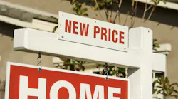 Home for sale sign with 'new price' signage added on top.