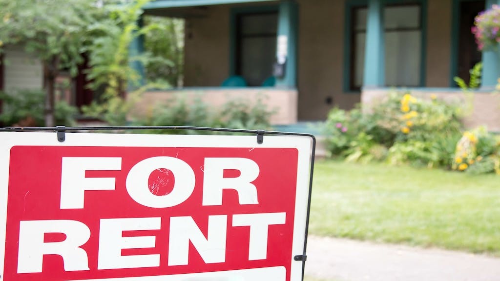A single-family rental home with a 'For Rent' sign in front