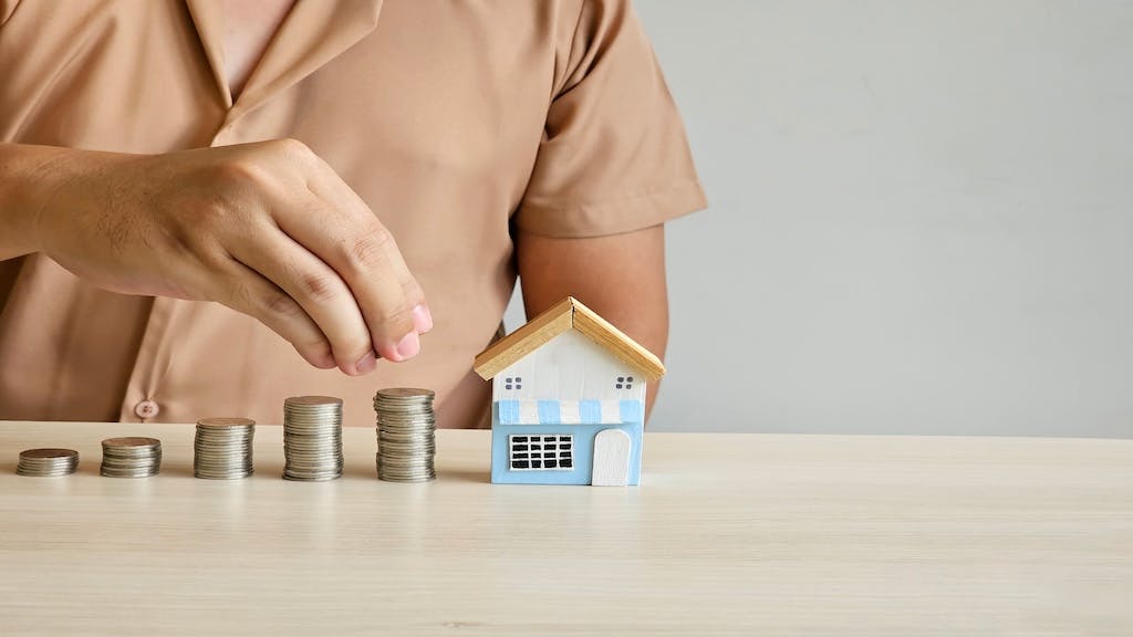 Coins are stacked in ascending order. A model home next to the coins indicates an increase in housing costs.
