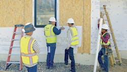 Construction workers being shown how to correctly apply housewrap on a new build Construction workers being shown how to correctly apply housewrap on a new build