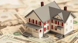 A model home sits on a pile of $20 bills
