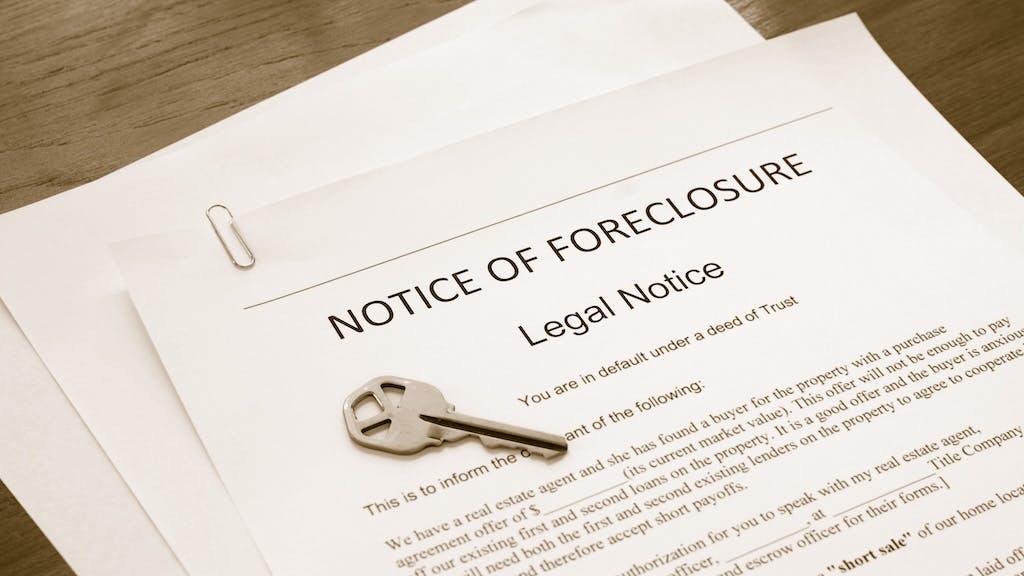 A document reading 'Notice of Foreclosure' with a key sitting on top of it