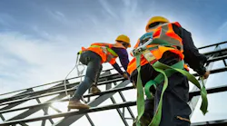 Two construction workers climb up a scaffolding.