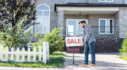 A man puts a 'Sale' sign outside his home