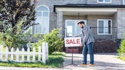 A man puts a 'Sale' sign outside his home A man puts a 'Sale' sign outside his home