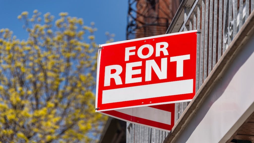 A red sign that reads 'For Rent' posted on a balcony