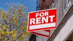 A red sign that reads 'For Rent' posted on a balcony