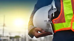 A construction worker in a safety vest holding a hard hat