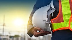 A construction worker in a safety vest holding a hard hat A construction worker in a safety vest holding a hard hat