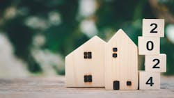 A wooden model home with blocks spelling out '2024' displayed next to it A wooden model home with blocks spelling out '2024' displayed next to it