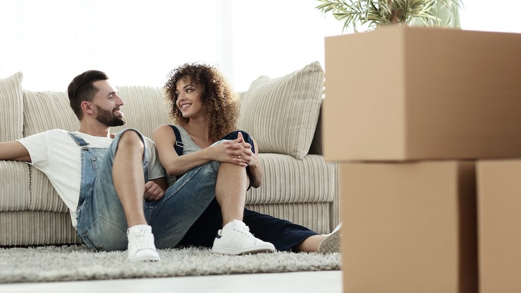 A couple sits on the living room floor of their rented home.