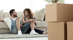 A couple sits on the living room floor of their rented home.