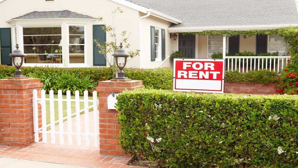 A single-family home with a 'For Rent' sign in the front yard