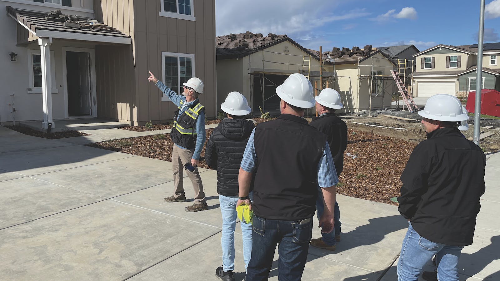 A crew of construction workers inspects the quality of a home under construction