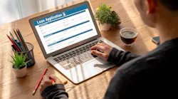 An individual fills out a loan application form on their laptop
