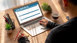 An individual fills out a loan application form on their laptop An individual fills out a loan application form on their laptop