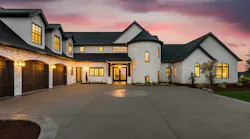 A luxury home with white exterior and expansive driveway
