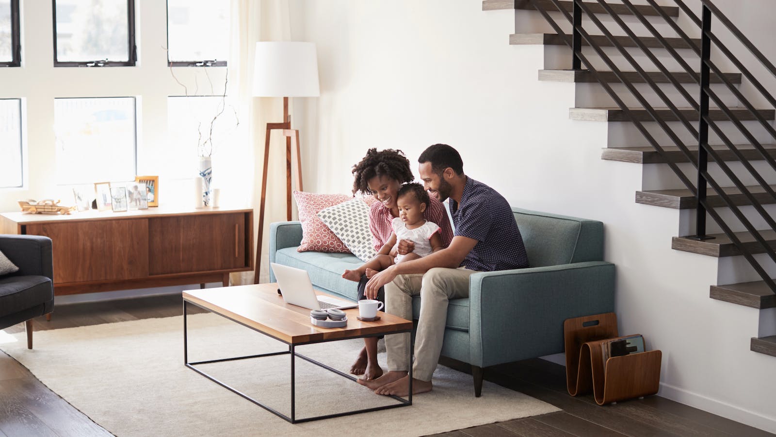 A family of three sitting on the couch in their home's living room