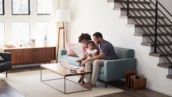 A family of three sitting on the couch in their home's living room A family of three sitting on the couch in their home's living room