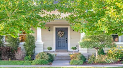 A door of a single-family home framed by trees