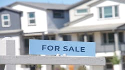 A closeup image of a 'For Sale' sign in front of a new home A closeup image of a 'For Sale' sign in front of a new home