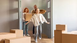 A family excitedly walks into their new home carrying moving boxes. A family excitedly walks into their new home carrying moving boxes.