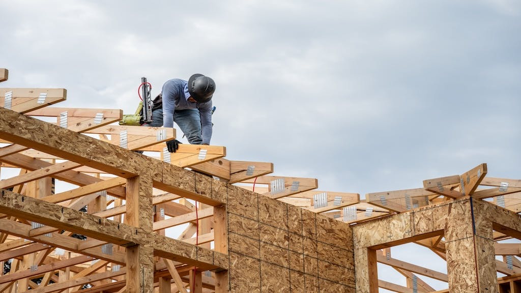 A builder works on the roof of a home