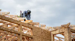 A builder works on the roof of a home