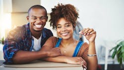 A young couple leans on moving boxes while holding up a set of house keys A young couple leans on moving boxes while holding up a set of house keys