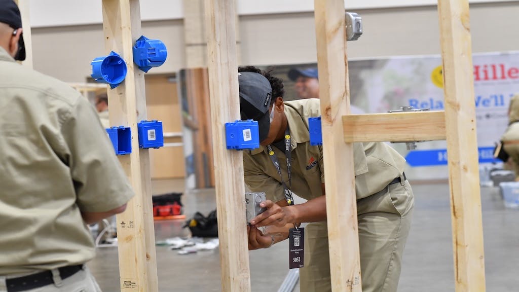 Students work at installing electrical outlets at a trade school