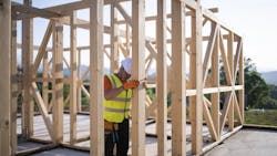 A construction worker erects the framing for a new home. A construction worker erects the framing for a new home.