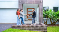 A young couple shakes hands with a real estate agent outside of their newly purchased home.