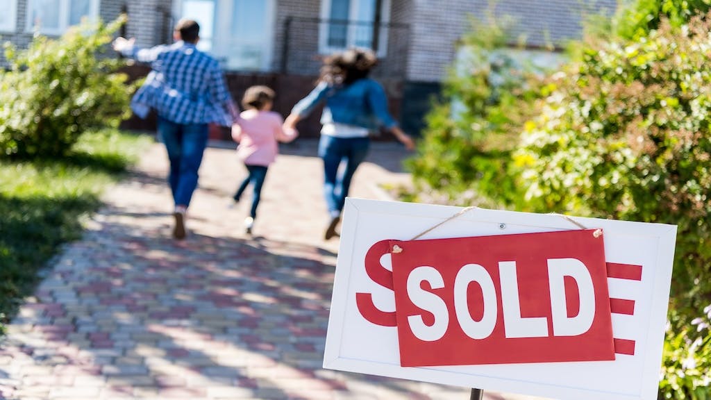 A family runs excitedly toward their recently purchased home.