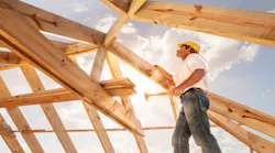 A roofer works on framing the roof of a home.