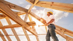 A roofer works on framing the roof of a home. A roofer works on framing the roof of a home.
