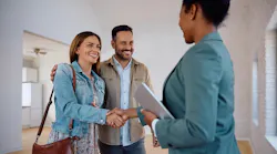 Homebuyers shake hands with a real estate agent who is showing them a home to buy.