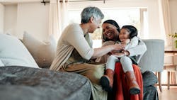 Three generations of women sit in a living room together laughing Three generations of women sit in a living room together laughing