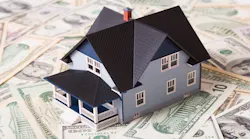 A model house sits on a pile of money