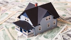 A model house sits on a pile of money A model house sits on a pile of money