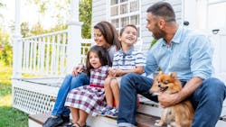 A family sits outside on the front porch of their home A family sits outside on the front porch of their home