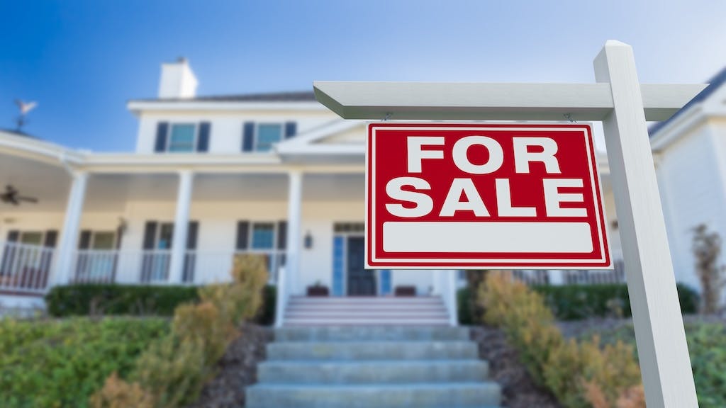 A home with a for sale sign in the front yard
