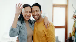 A smiling couple holds up a pair of keys to their new home
