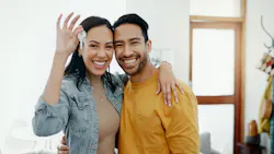 A smiling couple holds up a pair of keys to their new home