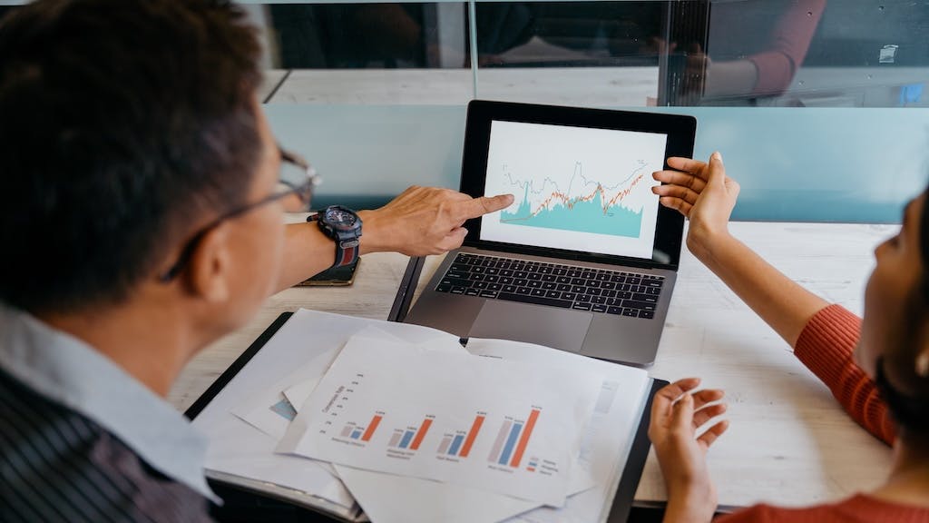 Two business partners look over data on a computer.