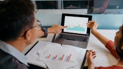 Two business partners look over data on a computer. Two business partners look over data on a computer.