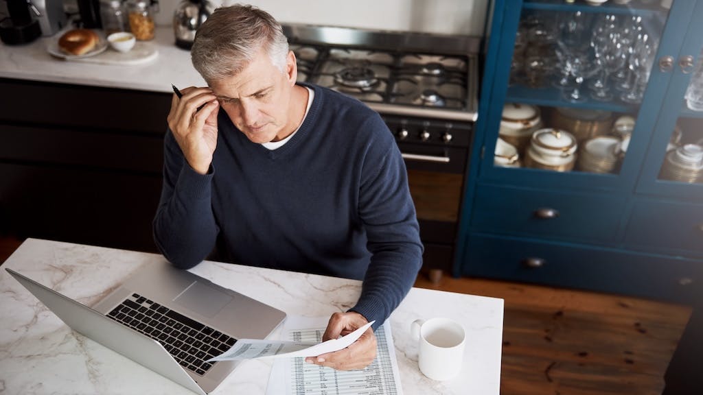 A man looks distressed as he reviews the budget and expenses for his home
