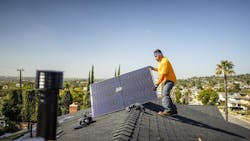 A worker pulls a solar panel onto a roof of a home A worker pulls a solar panel onto a roof of a home
