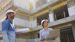 Two construction workers look over their work at a jobsite